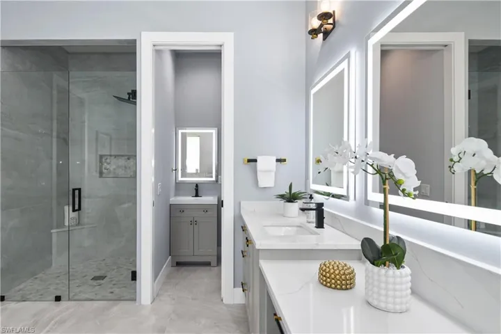 Bathroom with tile patterned floors, double sink vanity, and an enclosed shower