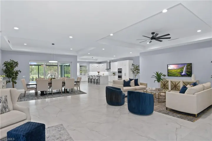 Tiled living room featuring ceiling fan and a raised ceiling