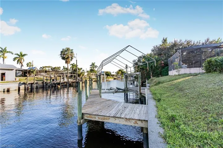 Dock area with a yard, a water view, and a lanai