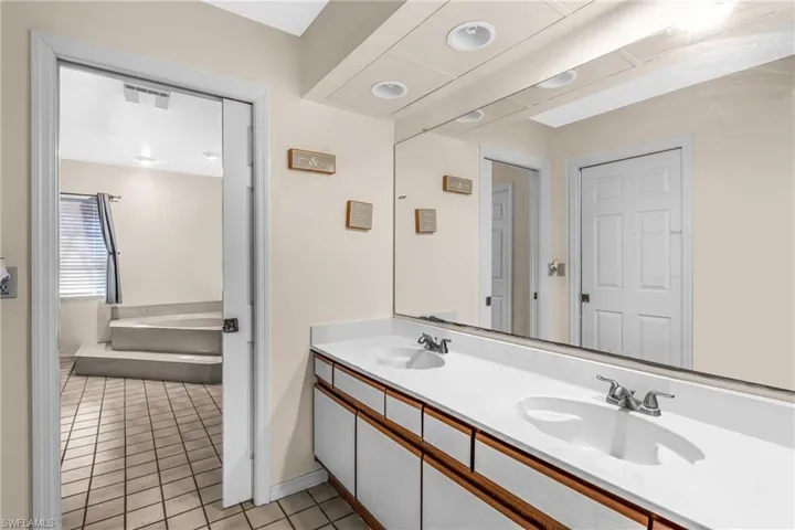Bathroom featuring tile patterned floors, vanity, and a bath