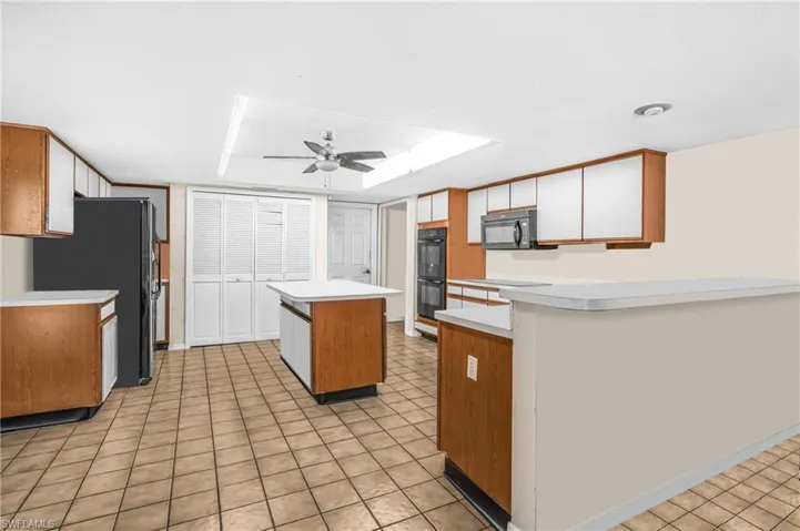 Kitchen with ceiling fan, a center island, and black appliances
