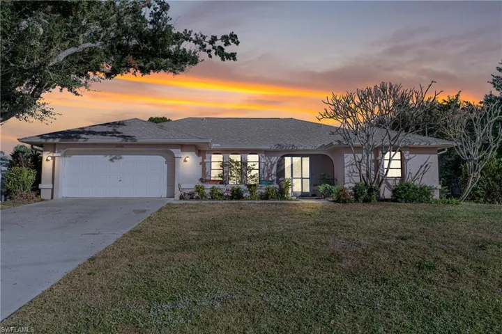 View of front of house featuring a lawn and a garage
