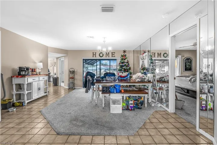 Kitchen with ceiling fan with notable chandelier, light tile patterned flooring, and white cabinetry