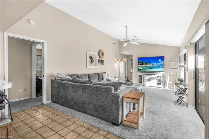 Living room featuring carpet, ceiling fan, and high vaulted ceiling