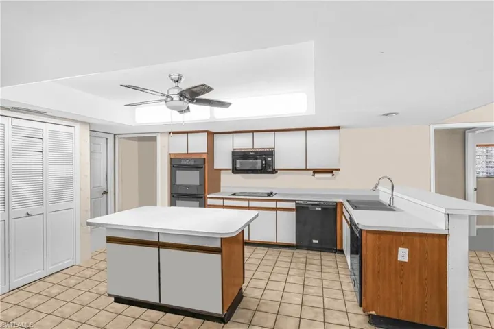 Kitchen featuring black appliances, a center island, white cabinets, and sink