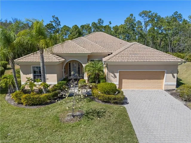 Mediterranean / spanish house featuring an attached garage, stucco siding, decorative driveway, and a front yard