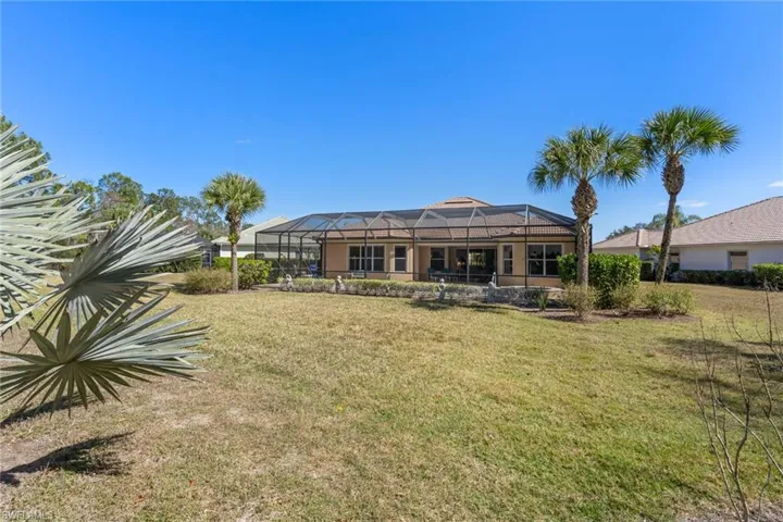 Back of property featuring a sunroom, a lanai, and a lawn