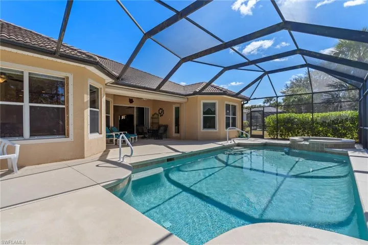 Relaxing pool / spa with glass enclosure, a sunroom, and a patio area