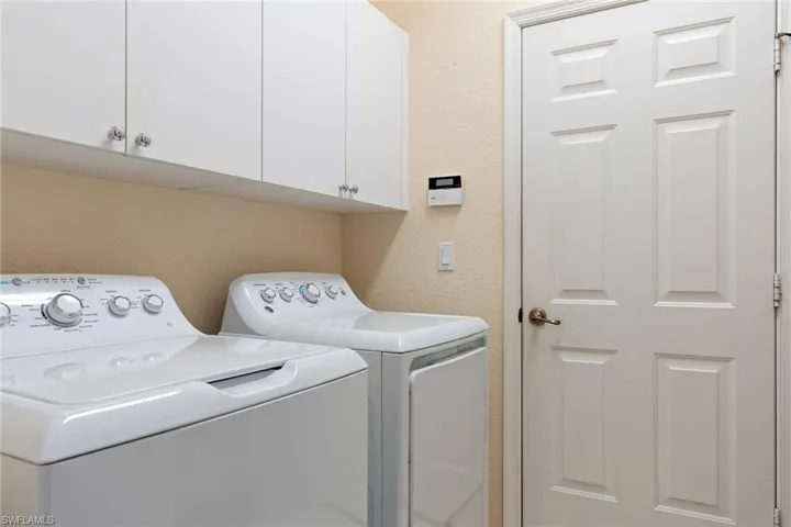 Laundry room featuring a textured wall, separate washer and dryer, and cabinet space