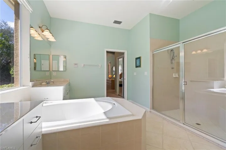 Bathroom featuring a garden tub, vanity, a stall shower, and light tile patterned flooring