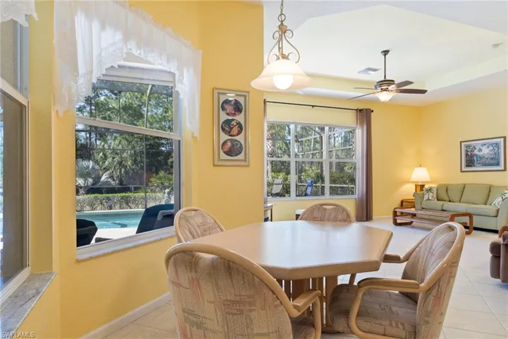 Dining area with ceiling fan, light tile patterned floors, and a raised ceiling