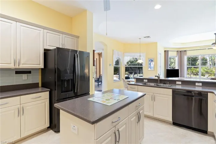 Kitchen featuring a ceiling fan, dark countertops, black appliances, pendant lighting, and a kitchen island