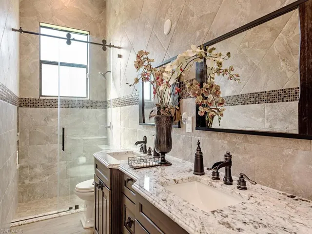 Bathroom featuring vanity, toilet, a wealth of natural light, and an enclosed shower