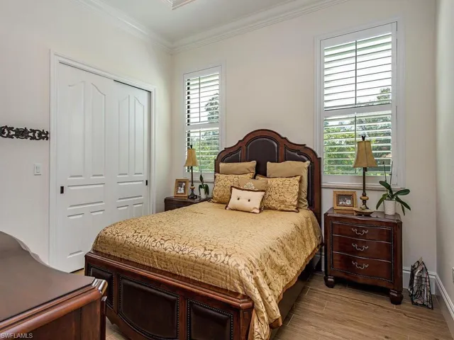 Bedroom with a closet, crown molding, and light hardwood / wood-style flooring