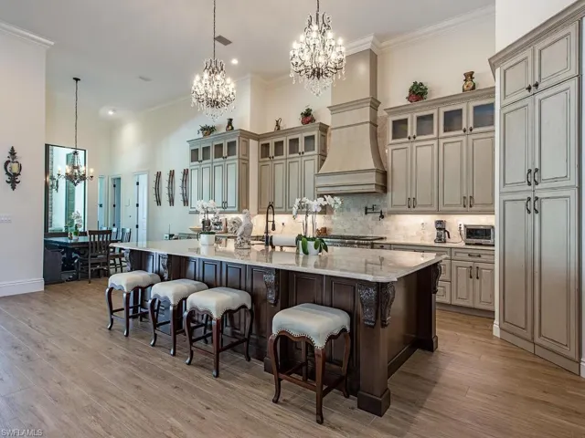 Kitchen featuring light wood-type flooring, a spacious island, a notable chandelier, and a breakfast bar