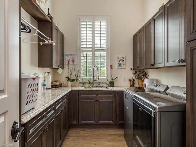 Laundry area with cabinets, washer and dryer, sink, and light hardwood / wood-style floors