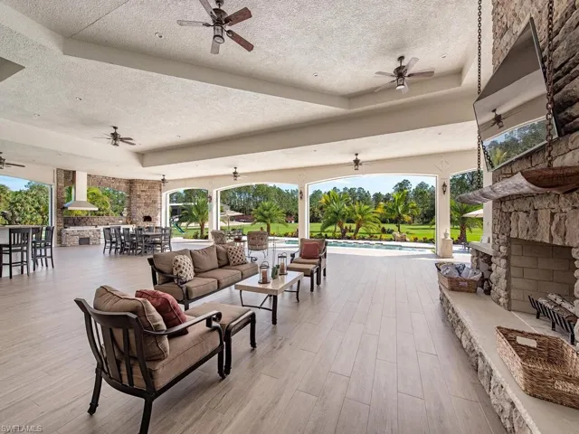 View of patio / terrace featuring an outdoor living space with a fireplace, a bar, and ceiling fan
