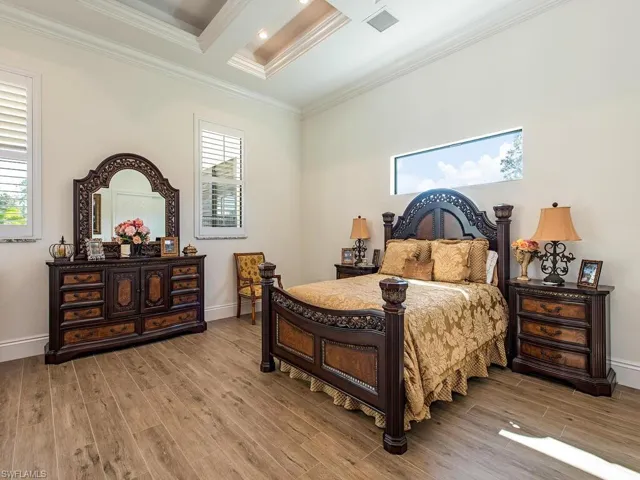 Bedroom featuring crown molding, coffered ceiling, light hardwood / wood-style flooring, and beam ceiling