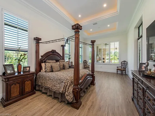 Bedroom featuring a tray ceiling, light hardwood / wood-style floors, and ornamental molding