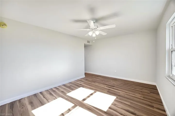 Unfurnished room with dark wood-style flooring and ceiling fan