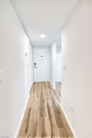 Hallway with light wood-style floors and baseboards