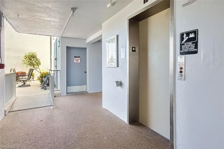 Hallway with elevator, speckled floor, and a textured wall