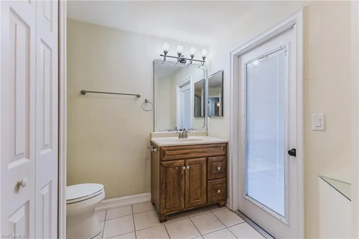 Bathroom with tile flooring, a wood-finish vanity with an integrated sink, a large mirror, and a five-light fixture