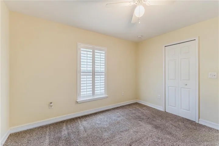 Carpeted room with a ceiling fan light fixture