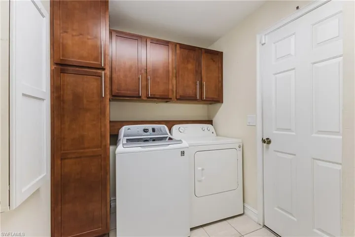 Laundry area with overhead and tall cabinetry, ceramic tile flooring, and a paneled door