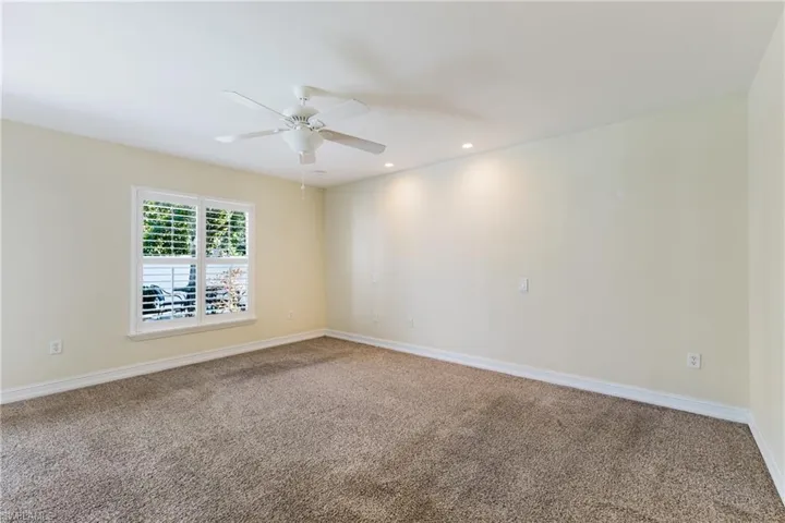 Carpeted room with a ceiling fan, recessed lighting, and a window featuring white plantation shutters