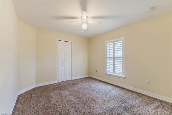 Interior room featuring neutral-toned walls, textured carpet flooring, and white baseboards