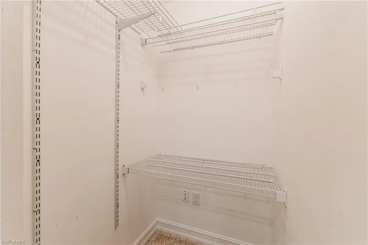Interior storage space featuring adjustable wire shelving, a carpeted floor, and white baseboard trim