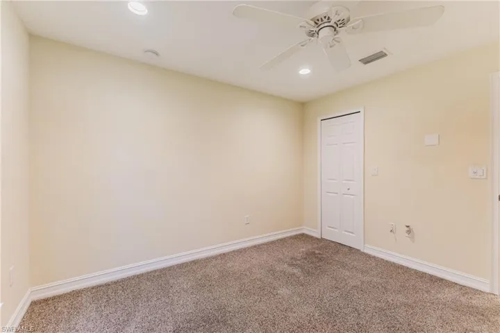 Interior room featuring neutral-toned walls, recessed lighting, a ceiling fan, and carpet flooring