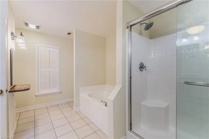 Bathroom featuring a glass-enclosed shower with white subway tile, a built-in shower bench, and a rainfall showerhead