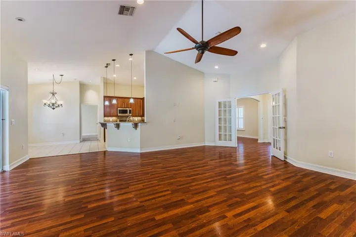 Spacious living area featuring wood-finish flooring, vaulted ceilings, and a ceiling fan