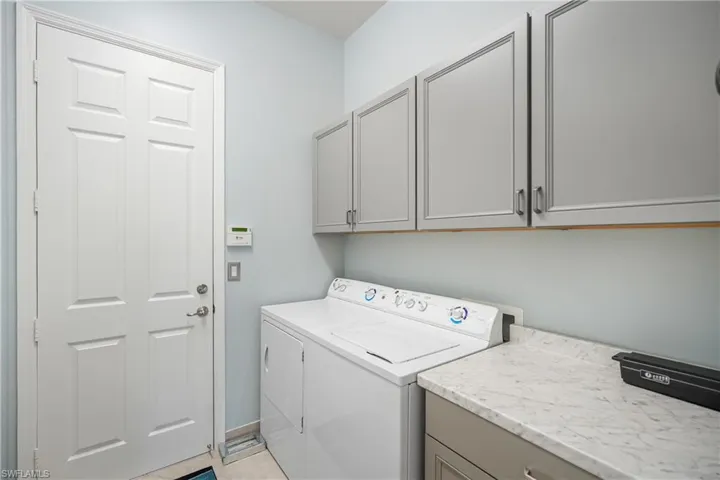 Laundry area featuring cabinets, light tile patterned floors, and separate washer and dryer