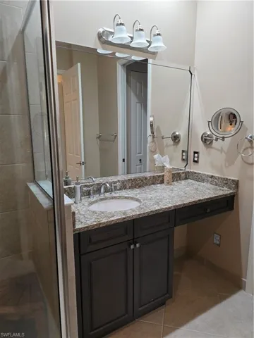 Bathroom featuring walk in shower, tile patterned floors, and vanity