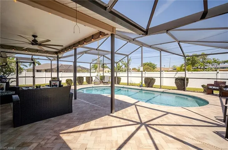 View of pool featuring glass enclosure, a sunroom, a patio, and ceiling fan