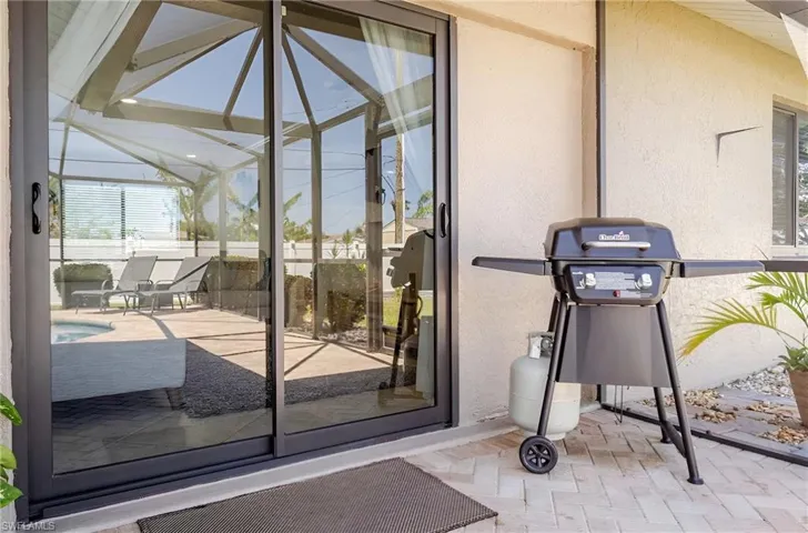 Doorway to property with a patio, stucco siding, a sunroom, and an outdoor pool