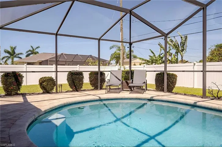 View of swimming pool with glass enclosure, a sunroom, and a fenced backyard