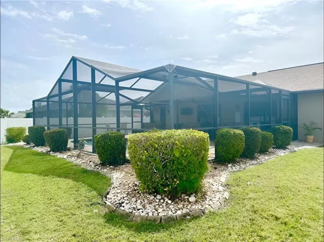 Back of property with a lanai, a sunroom, and a shingled roof