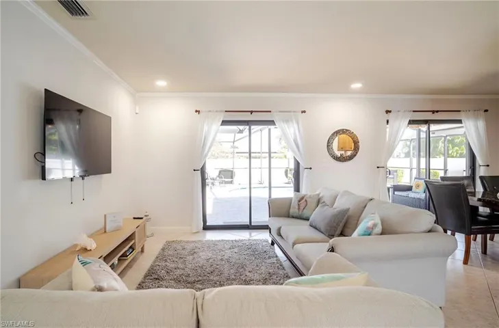Living area with ornamental molding, recessed lighting, and light tile patterned flooring