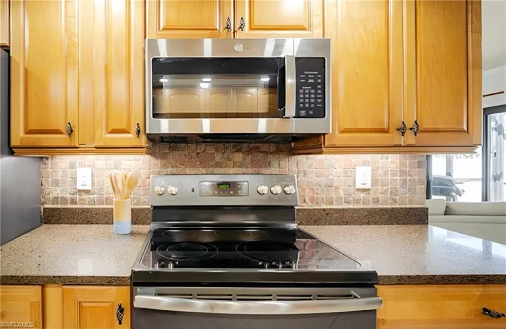 Kitchen featuring appliances with stainless steel finishes, dark stone countertops, and backsplash