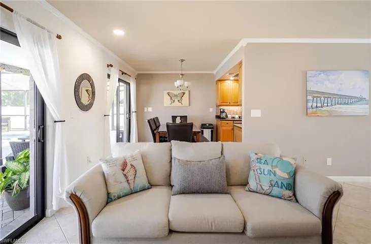 Living room featuring light tile patterned floors, ornamental molding, and a chandelier