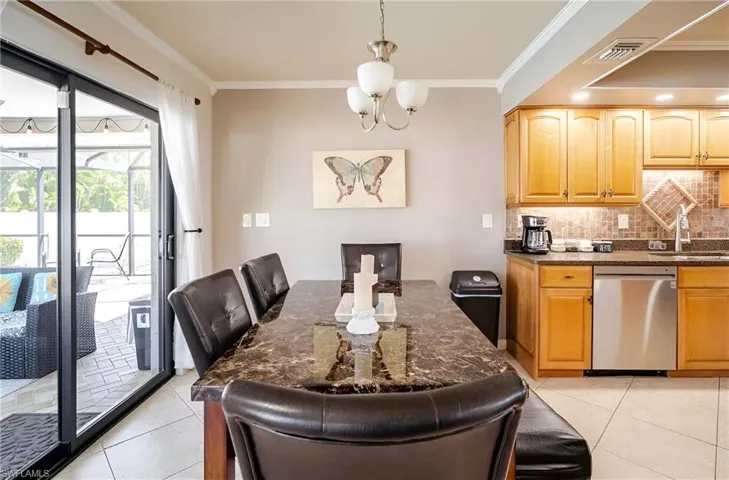 Dining room with crown molding, light tile patterned floors, and a chandelier