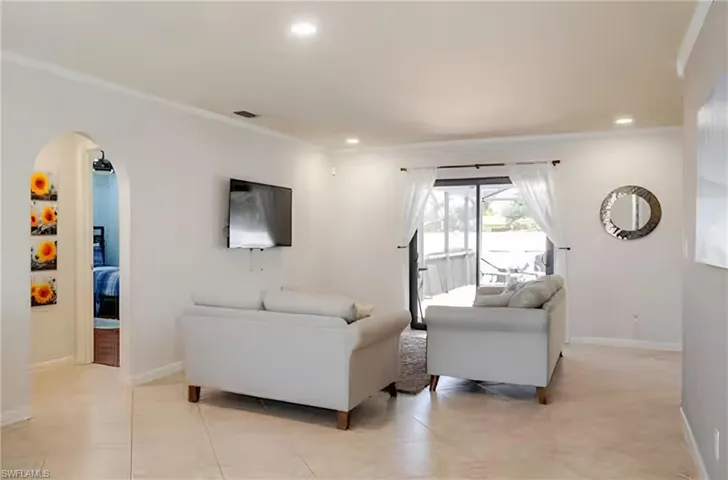 Living area featuring arched walkways, recessed lighting, and light tile patterned floors