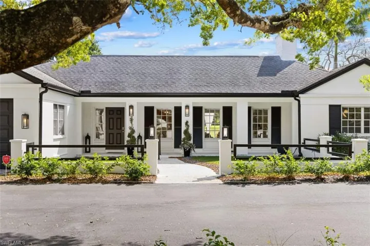 View of front of home featuring a porch, a chimney, a shingled roof, and a garage