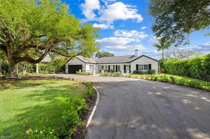 Single story home featuring a front lawn, asphalt driveway, a chimney, and an attached garage