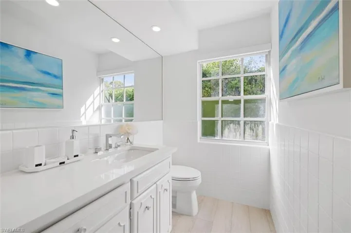 Bathroom featuring tile walls, wainscoting, vanity, and recessed lighting