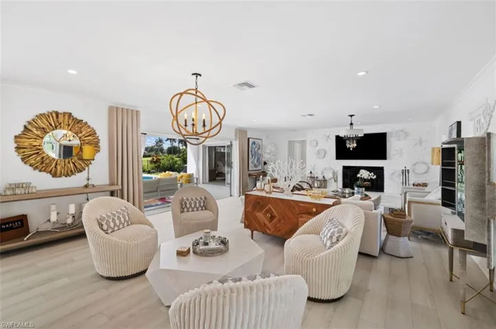 Living room with a chandelier, a fireplace, recessed lighting, wood finished floors, and crown molding